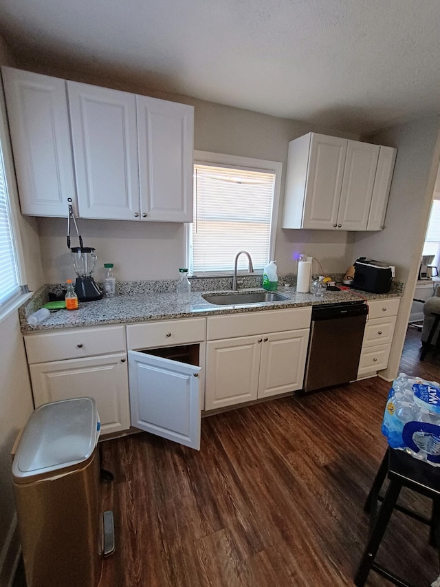 kitchen with stainless steel dishwasher, dark wood-style flooring, white cabinetry, and a sink