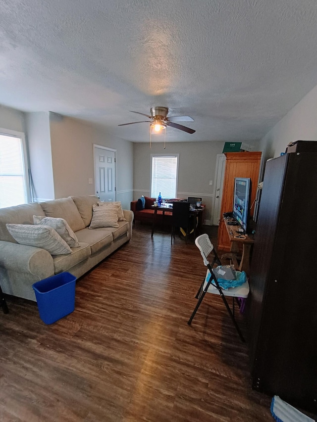 living room with dark wood finished floors, a ceiling fan, and a textured ceiling