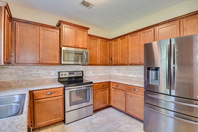 132 Running Creek Dr, North Augusta, SC 29860 - kitchen with appliances with stainless steel finishes, light countertops, brown cabinets, and backsplash