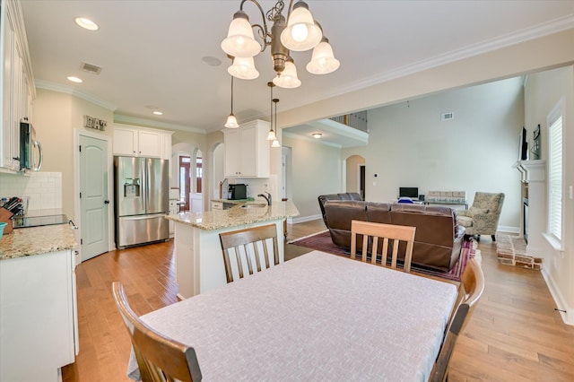 214 Torrey Pine Trl, Evans, GA 30809 - dining room featuring arched walkways, a chandelier, light wood-type flooring, ornamental molding, and baseboards