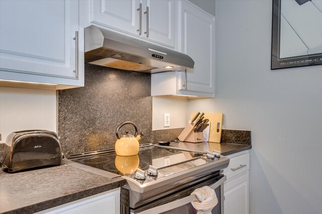 kitchen featuring backsplash, white cabinetry, and stove