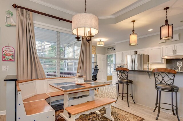 dining area featuring crown molding, a healthy amount of sunlight, and light hardwood / wood-style floors