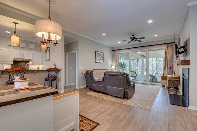 living room with ceiling fan, sink, light hardwood / wood-style floors, and ornamental molding