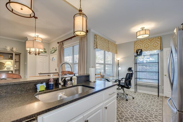 kitchen with white cabinets, stainless steel fridge, pendant lighting, and sink