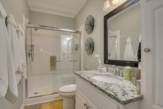 bathroom featuring vanity, a shower with door, hardwood / wood-style flooring, toilet, and ornamental molding