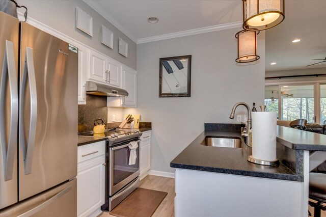 kitchen with a breakfast bar, sink, white cabinets, and stainless steel appliances