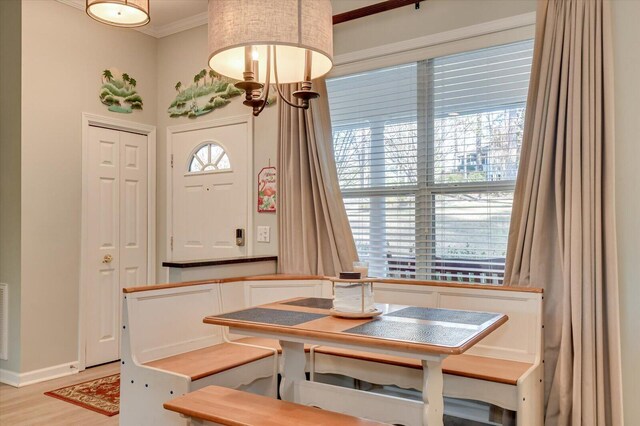 dining room featuring breakfast area, crown molding, and light hardwood / wood-style flooring