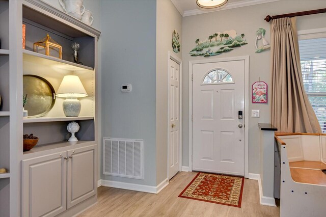 entryway with light wood-type flooring and crown molding