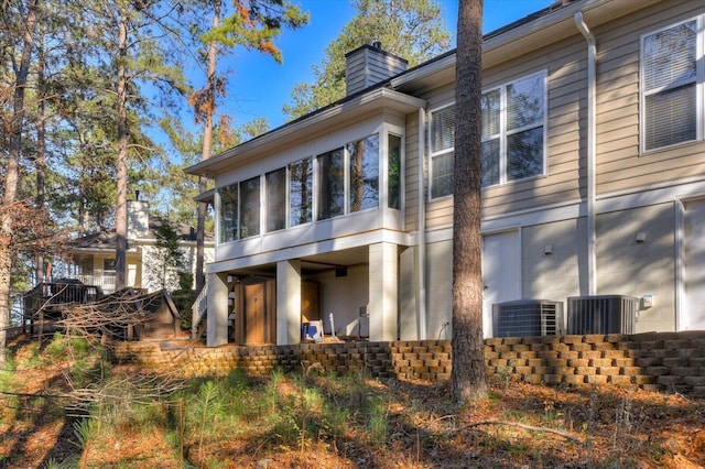 rear view of property featuring a sunroom and central AC unit