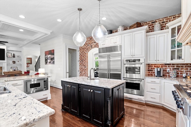 462 Armstrong Way, Evans, GA 30809 - kitchen with built in appliances, a kitchen island with sink, arched walkways, dark cabinetry, and dark wood-style flooring