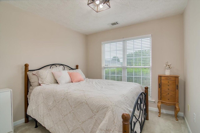 bedroom featuring light carpet and a textured ceiling