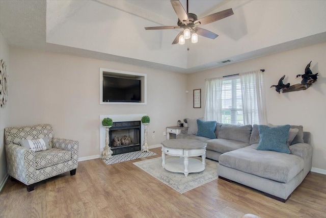 living room with a raised ceiling, ceiling fan, and hardwood / wood-style floors