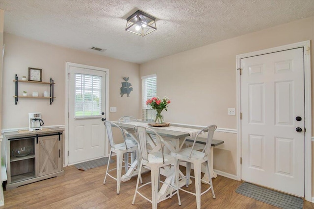 dining space featuring light hardwood / wood-style floors and a textured ceiling