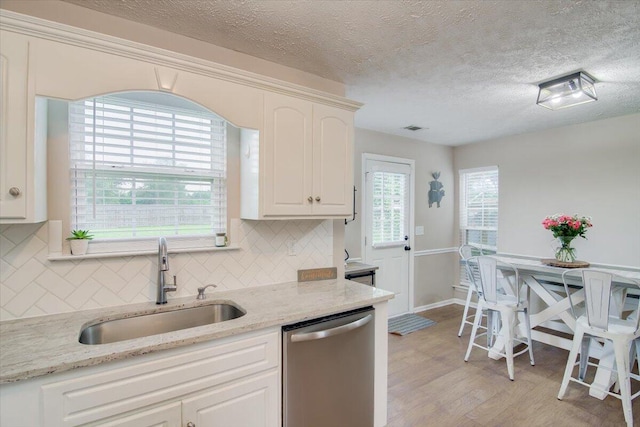 kitchen with dishwasher, white cabinets, sink, decorative backsplash, and light stone counters