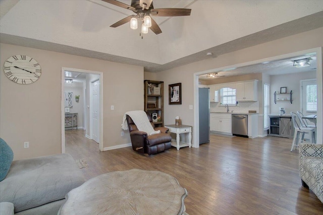 living room with a textured ceiling, ceiling fan, sink, and light hardwood / wood-style flooring