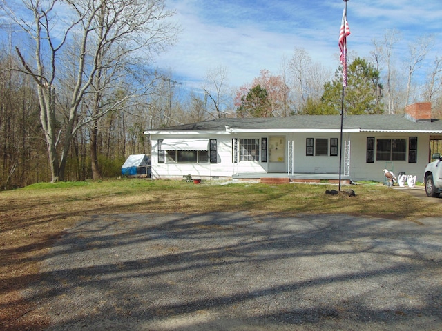 view of front facade featuring a porch, a chimney, and a front yard