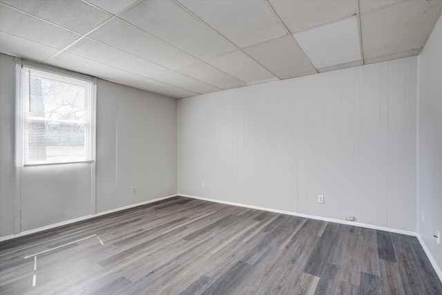 spare room with wood finished floors, baseboards, and a paneled ceiling