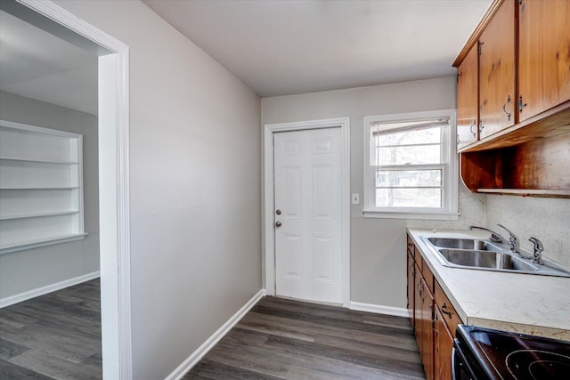 kitchen with baseboards, dark wood finished floors, a sink, light countertops, and black range with electric stovetop