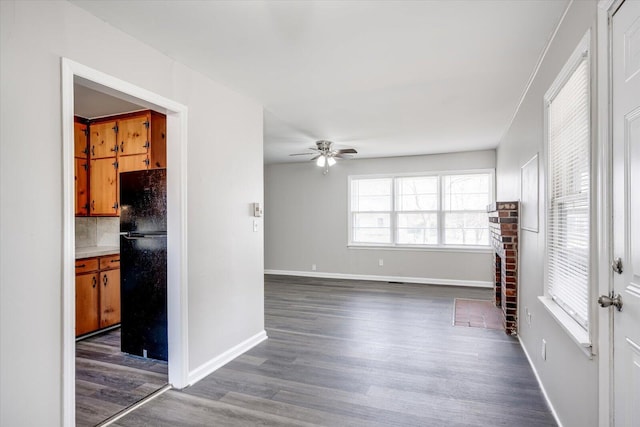 unfurnished living room with baseboards, wood finished floors, and a ceiling fan