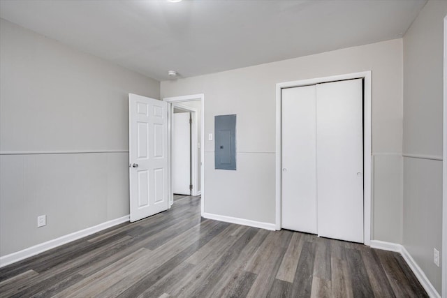 unfurnished bedroom featuring electric panel, wood finished floors, a closet, and baseboards