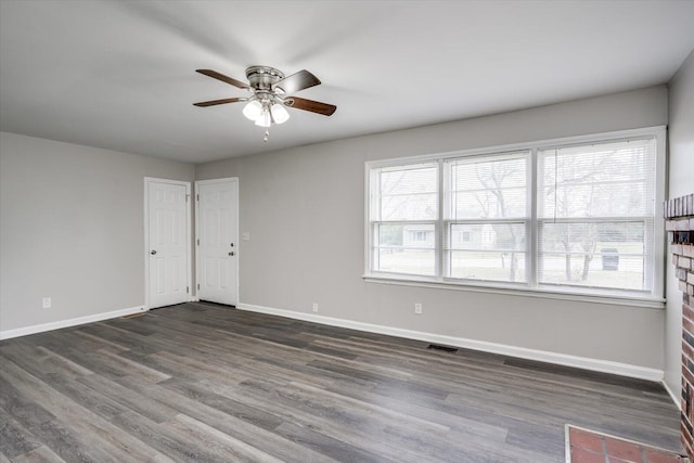 empty room featuring dark wood-style floors, visible vents, baseboards, and a ceiling fan