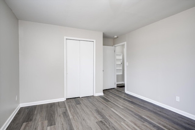 unfurnished bedroom featuring a closet, baseboards, and wood finished floors