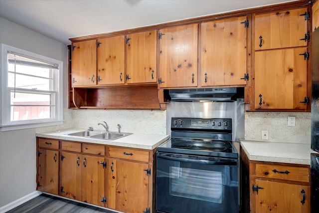 kitchen featuring light countertops, black electric range oven, under cabinet range hood, and a sink