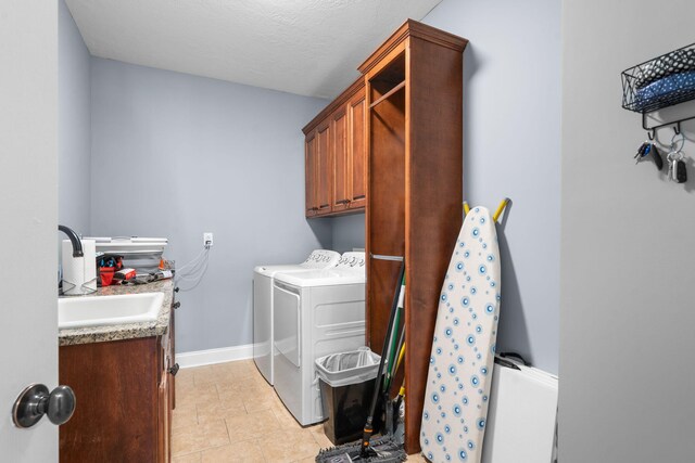 laundry area with a textured ceiling, cabinets, separate washer and dryer, and sink