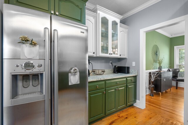 kitchen featuring stainless steel refrigerator with ice dispenser, light stone counters, ornamental molding, light hardwood / wood-style floors, and white cabinetry