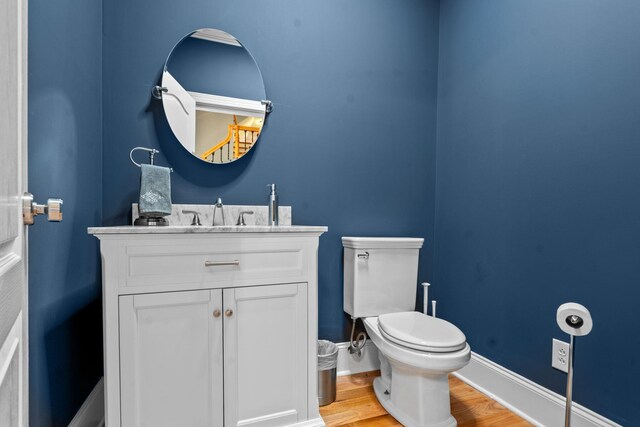 bathroom with wood-type flooring, vanity, and toilet