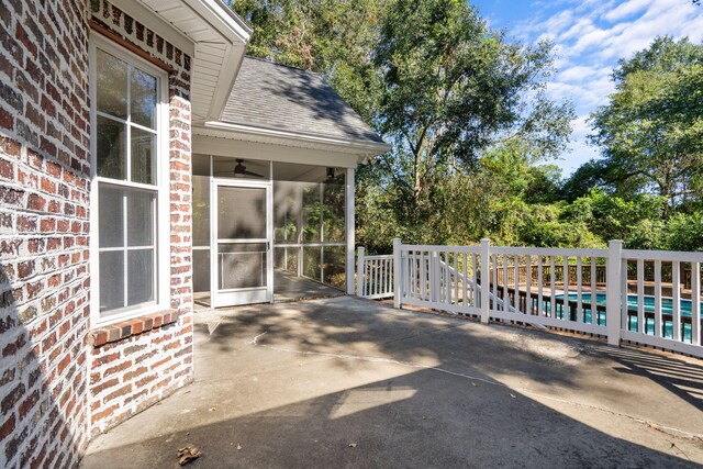 view of patio / terrace with a sunroom, ceiling fan, and a fenced in pool