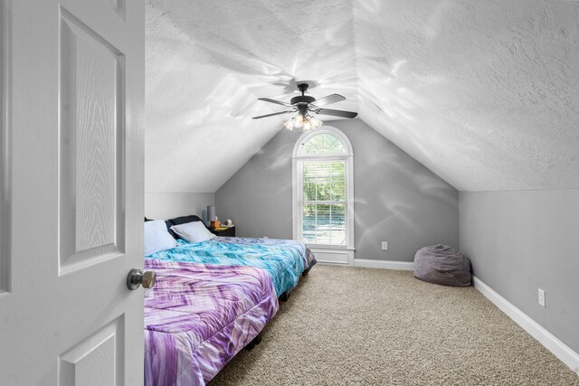 bedroom with carpet, ceiling fan, lofted ceiling, and a textured ceiling