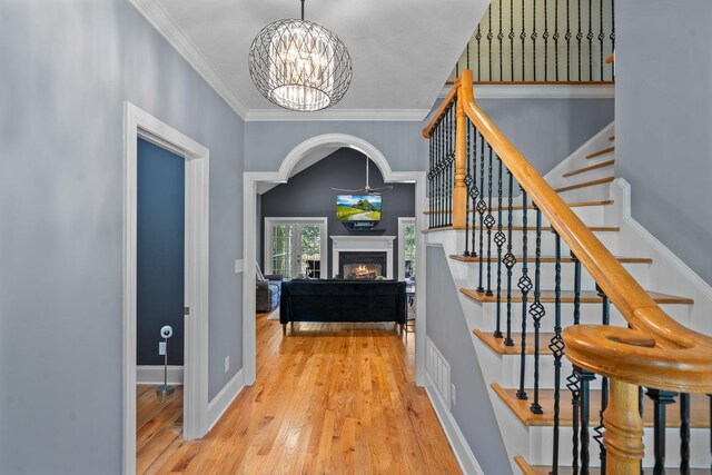 interior space featuring crown molding, wood-type flooring, and a notable chandelier