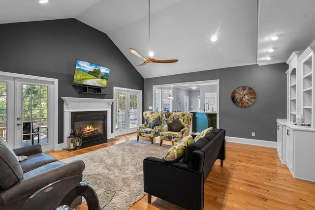 living room with ceiling fan, a healthy amount of sunlight, vaulted ceiling, and light hardwood / wood-style floors