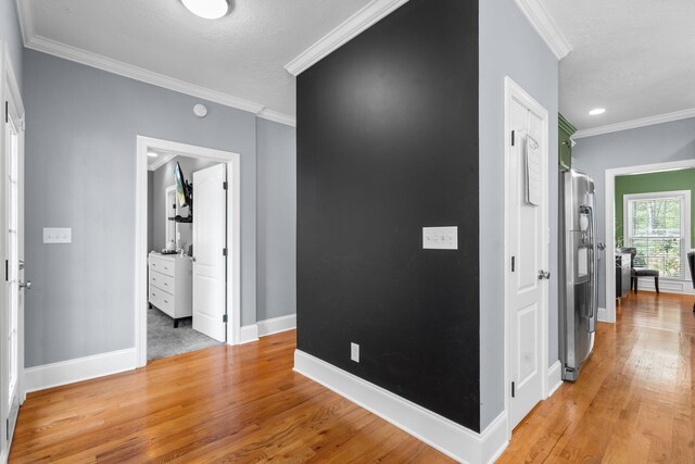 hallway with light hardwood / wood-style flooring and ornamental molding