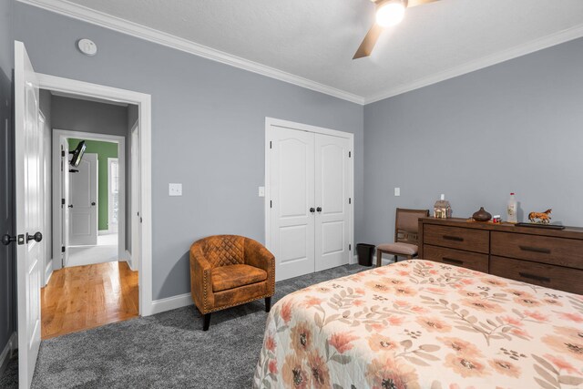 bedroom featuring a closet, dark carpet, ceiling fan, and crown molding