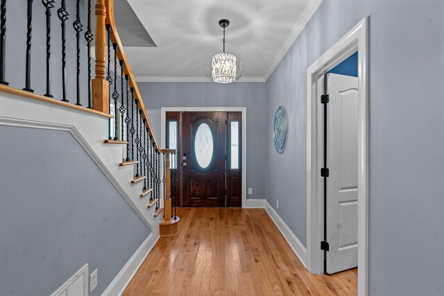 foyer entrance featuring a notable chandelier, ornamental molding, and light hardwood / wood-style flooring