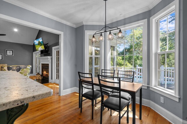 dining space with hardwood / wood-style flooring, a notable chandelier, lofted ceiling, and crown molding