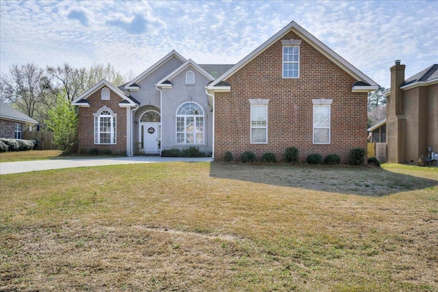 traditional home with brick siding, a front yard, and fence