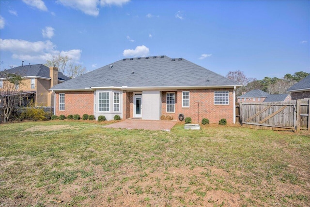 rear view of property featuring fence, a lawn, brick siding, and a patio area