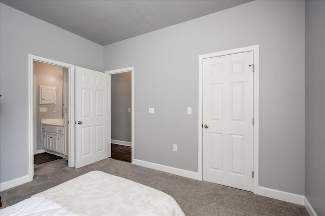 bedroom with dark colored carpet, connected bathroom, and baseboards