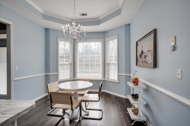 dining space with a notable chandelier, visible vents, a raised ceiling, and wood finished floors