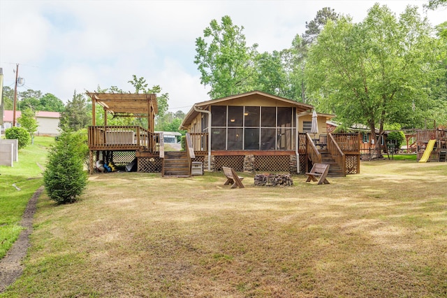 back of house featuring stairs, an outdoor fire pit, a sunroom, a deck, and a lawn