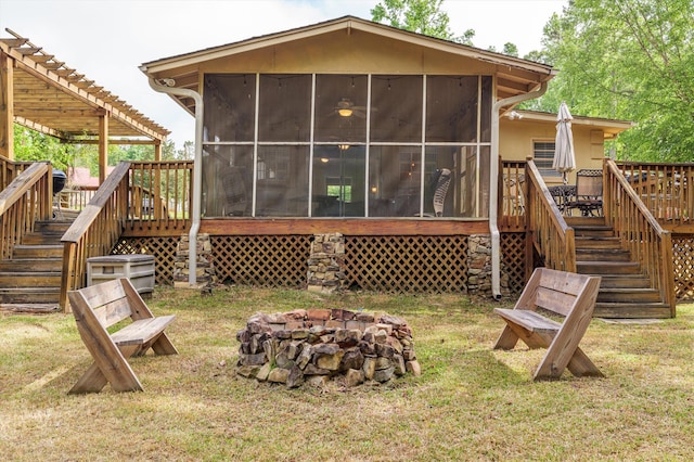 back of property featuring stairway, a lawn, a sunroom, and an outdoor fire pit