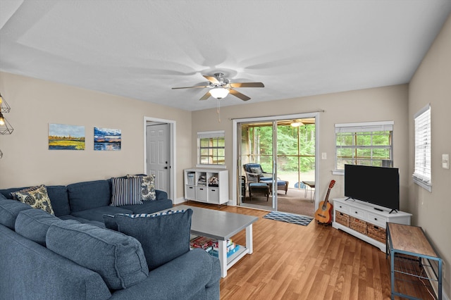 living area featuring a ceiling fan, baseboards, a healthy amount of sunlight, and light wood finished floors