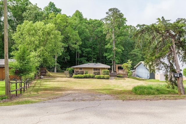 ranch-style house featuring a deck, an outbuilding, and a front lawn