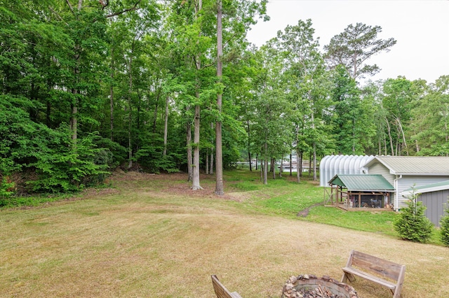 view of yard with an outdoor structure, a fire pit, and exterior structure