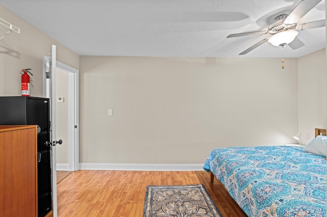 bedroom with light wood-style floors, baseboards, and a ceiling fan