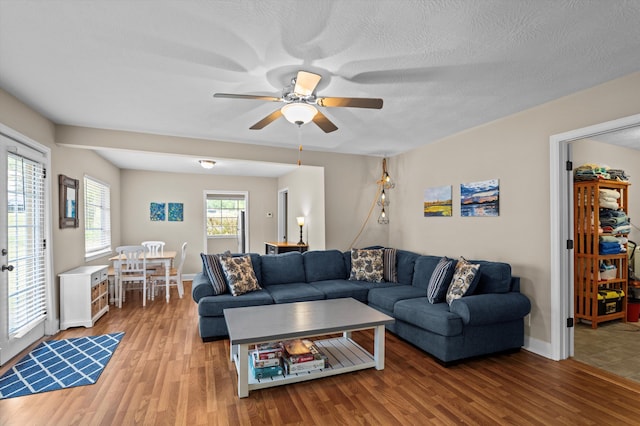 living room featuring light wood-style floors, baseboards, and ceiling fan