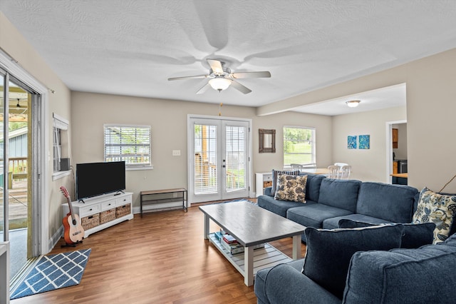 living area with a textured ceiling, ceiling fan, french doors, and wood finished floors